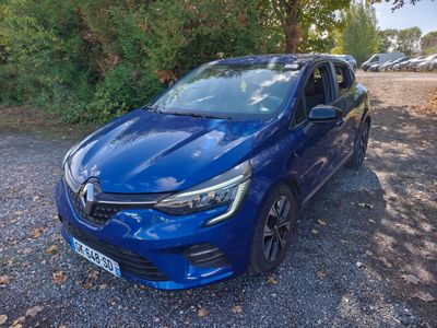 a blue car parked in a gravel lot next to trees