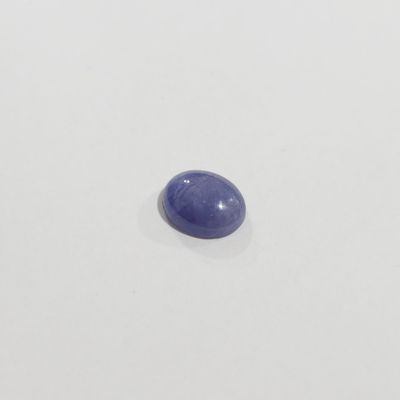 un saphir bleu de forme ovale posé sur une surface blanche