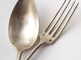 a silver spoon and a fork on a white surface