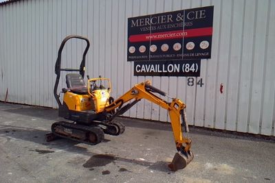 une petite pelleteuse jaune garée devant un immeuble