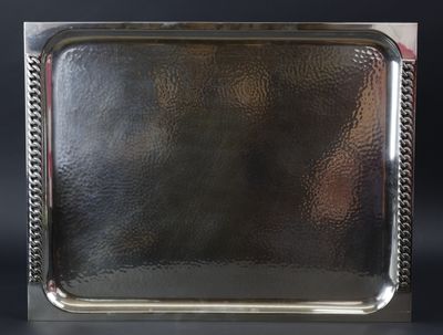 un plateau en argent muni d'une poignée, posé sur une table noire