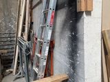 une échelle appuyée contre un mur, à côté d'un tas de bois