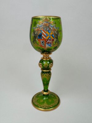 a green glass with a gold base and a coat of arms on it