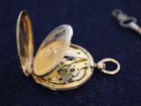 a gold pocket watch sitting on a black surface