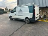 une camionnette blanche garée sur un parking, les portes ouvertes