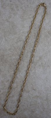 un gros plan d'un collier avec une chaîne en or posé sur une surface blanche