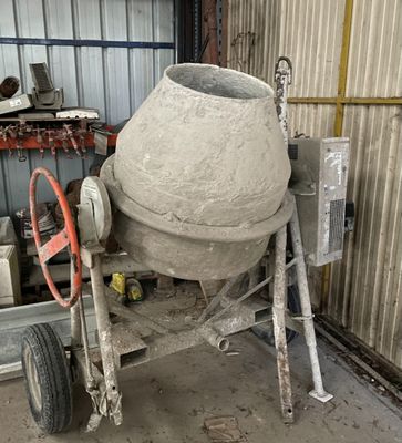 une bétonnière rangée dans un garage, dont une roue repose sur un chariot