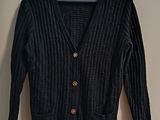 black cardigan sweater hanging on a hanger on a wall