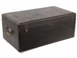 une vieille valise noire posée sur une surface blanche