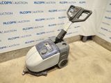 a close up of a floor scruber on the ground in front of a wall