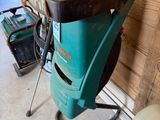 a green and black lawn mower sitting on a stand in a garage