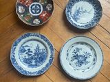 four blue and white plates sitting on top of a wooden floor