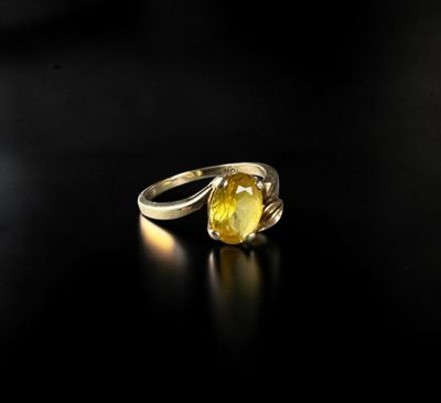 a close up of a yellow sapphire ring on a black surface