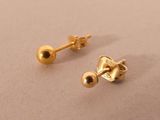 two pairs of gold stud earrings sitting on top of a table