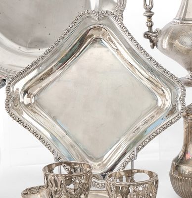 un plateau en argent avec des tasses et des soucoupes en argent posées sur une table