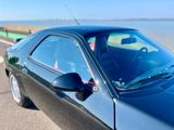 une voiture noire garée sur le bord de la route, près de l'eau
