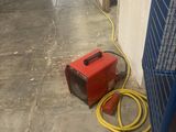 a red heater and a yellow hose on the floor