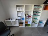 a room with a desk, shelves, and a chair in it