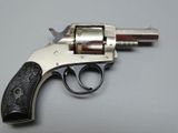 un revolver argenté à la crosse noire posé sur une table blanche