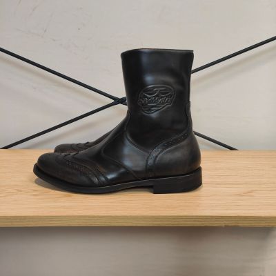 une paire de bottes en cuir noir posée sur une étagère en bois