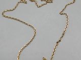 a close up of a gold necklace with a chain on a white surface