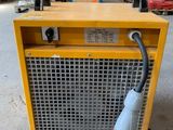 a yellow and black electric heater sitting on top of a cement floor