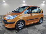 une photo d'une petite voiture orange garée dans un garage