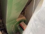a green trash can sitting in the corner of a bathroom