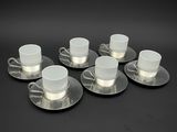 six tasses et soucoupes, posées sur une surface noire