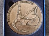 une image représentant une médaille en métal sur laquelle figurent un bateau et un drapeau