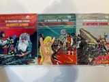three comics are lined up on a shelf in front of a white background