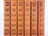 six vieux livres sont alignés sur une surface blanche