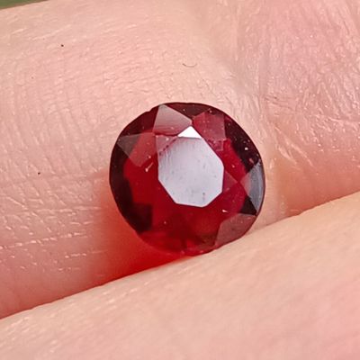 un gros plan sur le doigt d'une personne, sur lequel est monté un diamant rouge