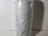 un rouleau de plastique emballé dans du plastique posé sur une surface blanche