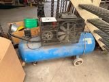 a blue air compressor sitting on the floor next to a pile of boxes
