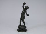 an antique bronze figurine of a boy holding a ball