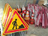 un tas de panneaux de chantier et de cônes posés par terre