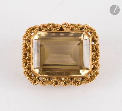 une bague en or sertie d'une émeraude entourée d'un motif en forme de corde