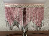 pink beaded lamp shade with silver fringes on a wooden table