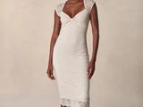 une femme en robe blanche prend la pose pour une photo