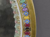 a mirror that has a gold frame with colorful flowers on it