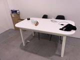 une table blanche avec deux chaises et un sac noir posé dessus