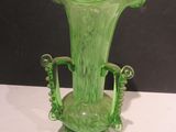 a green glass vase sitting on a white table
