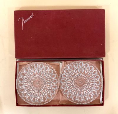deux dessous de verre en verre dans une boîte rouge posée sur une table