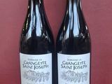 two bottles of wine sitting on top of a table next to each other