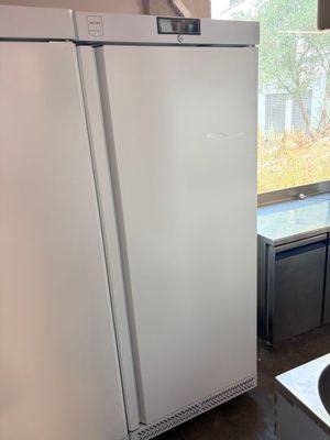 a white refrigerator in a kitchen with a sink and a window