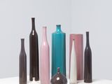 cinq vases de couleurs différentes posés sur une table blanche