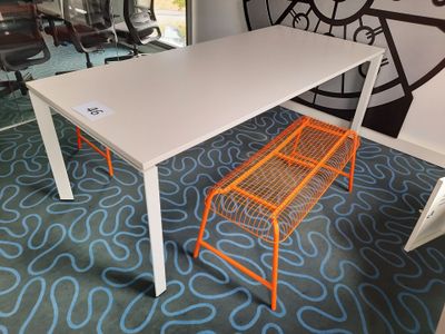 a white table with orange chairs in a room with a clock on the wall