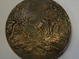 a gold medal with a picture of a man and a woman on it