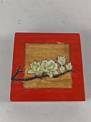 une petite boîte rouge décorée d'une peinture représentant des fleurs